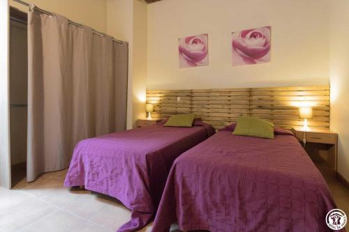 Dos camas en una habitación con sábanas moradas. en Fuji, en Pibrac