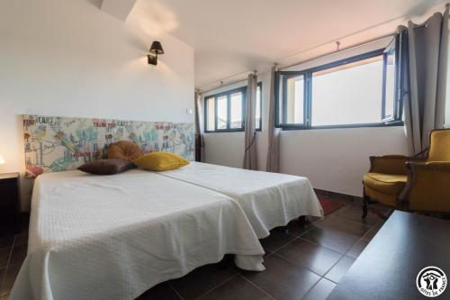 a bedroom with a bed with a white blanket and a window at Le hérisson in Aurignac