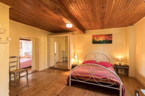 a bedroom with a bed with a wooden ceiling at Les platanes in Aignes