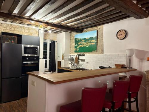 a kitchen with a counter with red chairs and a clock at Caen duplex T2 confort 18è s coeur de ville avec Vayny in Caen