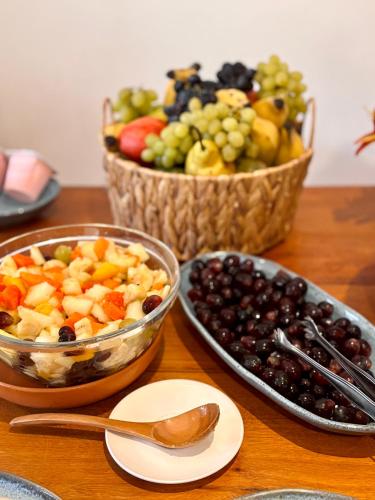 a table with two baskets of fruit and a bowl of grapes at Pousada Porto Fino in Cabo Frio