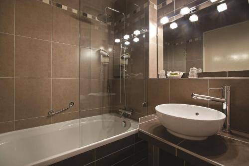 a bathroom with a tub and a sink and a mirror at Parc Hôtel in Wangenbourg
