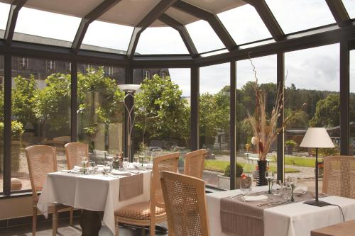 a dining room with white tables and chairs and windows at Parc Hôtel in Wangenbourg