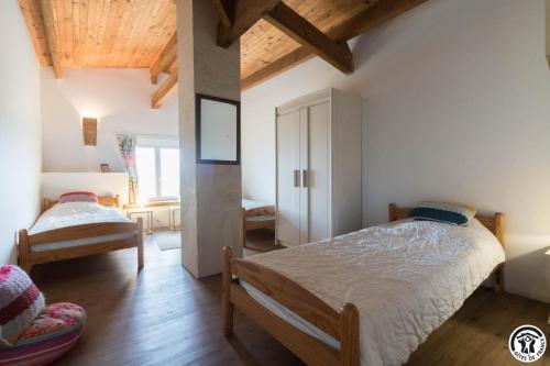 a bedroom with two beds in a room with wooden ceilings at Le gîte des oiseaux in Montbernard
