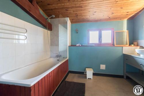 a bathroom with a bath tub and a sink at Le gîte des oiseaux in Montbernard