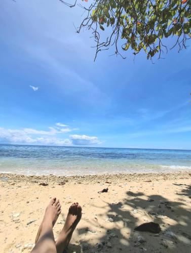 a person sitting on a beach with their feet in the sand at WUJOB Beach Campsite in Boljoon
