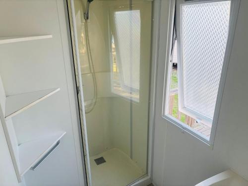 a shower with a glass door next to a window at camping le clos fleuri in Vic-la-Gardiole