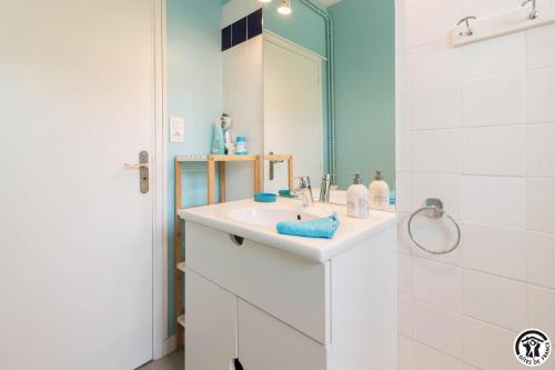 a white bathroom with a sink and a mirror at Les lilas in Aussonne
