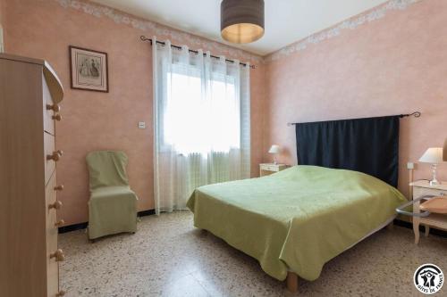 a bedroom with a green bed and a window at Les hortensias in Aussonne