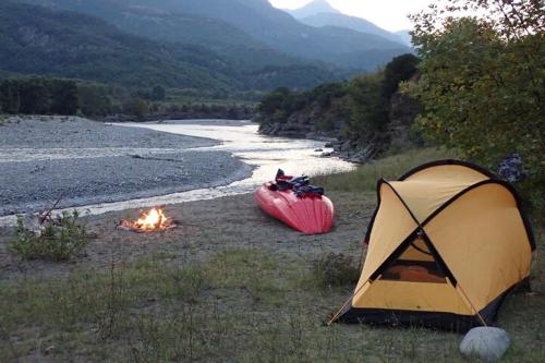 a tent and a kayak next to a river at Micro Africa Camping Site in Karpen