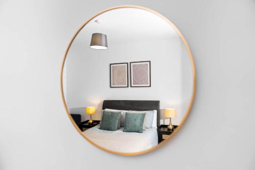 a mirror reflecting a bedroom with a bed and pillows at Stylish New 2-Bed Apartment in JQ in Birmingham