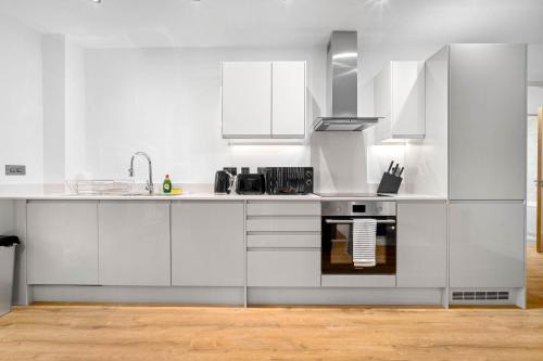 a white kitchen with white cabinets and a sink at Stylish New 2-Bed Apartment in JQ in Birmingham