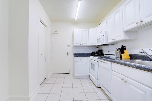 a white kitchen with a sink and a refrigerator at This Apt is Perfect For Business Trips or a Relaxing Vacation in Arlington