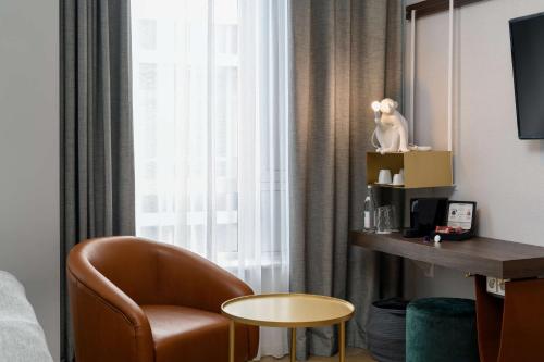 a hotel room with a chair and a window at Flightgate Munich Airport Hotel, a member of Radisson Individuals in Hallbergmoos
