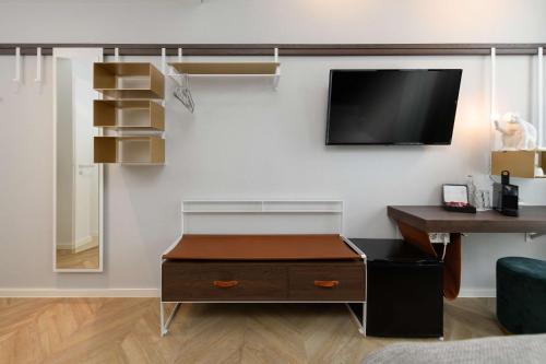 a living room with a desk and a tv on a wall at Flightgate Munich Airport Hotel, a member of Radisson Individuals in Hallbergmoos