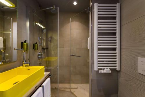 a bathroom with a yellow sink and a shower at Flightgate Munich Airport Hotel, a member of Radisson Individuals in Hallbergmoos