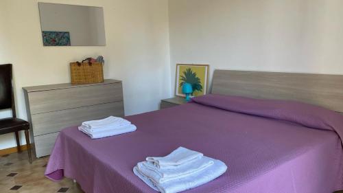 Un dormitorio con una cama morada con toallas encima. en Villetta Eliamare, en San Cataldo