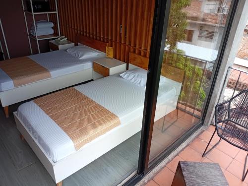 two beds in a room with a window at Hotel Momotus Tuxtla - Desayuno opcional in Tuxtla Gutiérrez