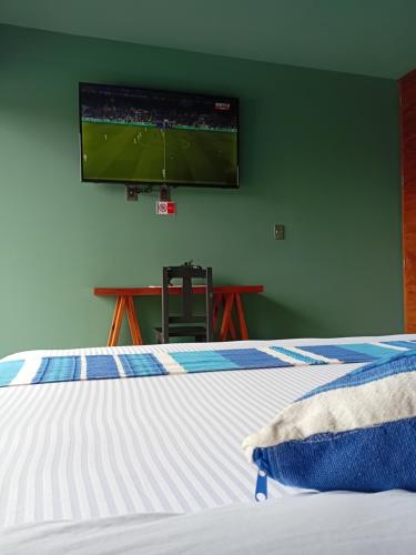 a bedroom with a bed with a tv on the wall at Hotel Momotus Tuxtla - Desayuno opcional in Tuxtla Gutiérrez
