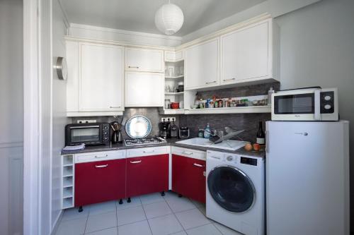 une cuisine avec des armoires blanches et une machine à laver dans l'établissement Lovely & Quiet à Montmartre, à Paris