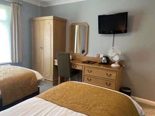 a hotel room with two beds and a desk with a mirror at Exeter Court Hotel in Exeter