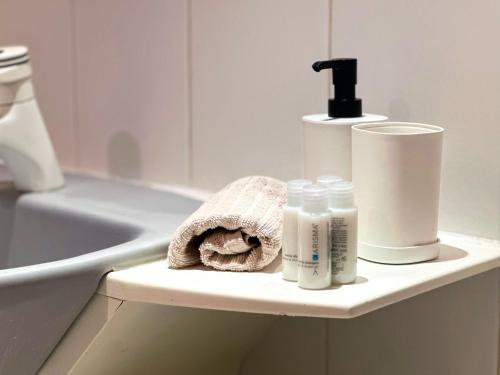 a bathroom with a sink and toiletries on a shelf at Le Golf Comme Jardin Dormez au Cœur du Parcours in Lésigny