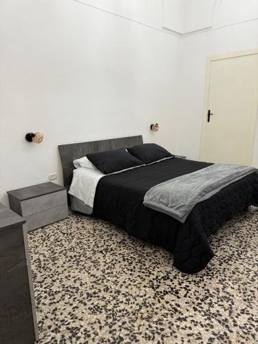 a bedroom with a bed with a black comforter at MiMì House in Nardò