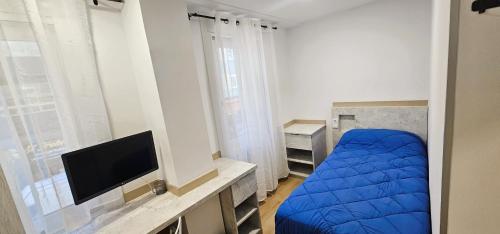 a bedroom with a blue bed and a flat screen tv at Vacansis Habitaciones y Alojamientos A Coruña in Visma