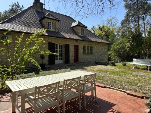 une table et deux chaises devant une maison dans l'établissement Le Peruguet - maison avec piscine et bois privé, à Margueron