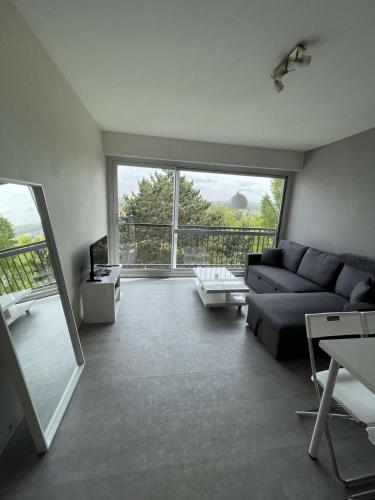 a living room with a couch and a large window at Sky - Superbe appartement lumineux et cosy in Villers-sur-Mer