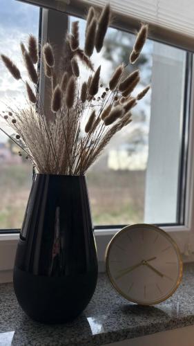 a clock and a vase with some dried plants in it at Ferienwohnung Fürstenberg - Storch in Fürstenberg-Havel