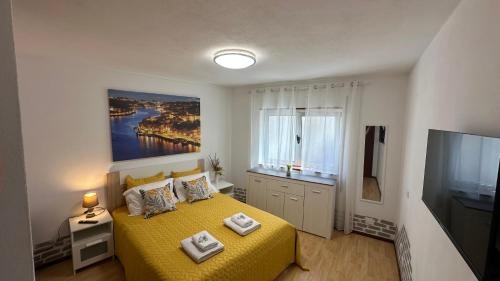 ein Schlafzimmer mit einem gelben Bett und einem TV in der Unterkunft Almeida's House by Férias em Figueira in Figueira da Foz