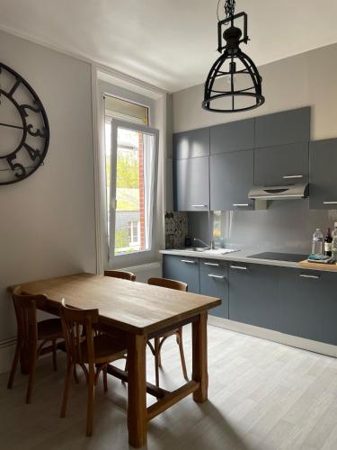 une cuisine avec une table, des chaises et une horloge dans l'établissement Villa Volclair Spacieux Duplex à 50m de la plage, à Mers-les-Bains