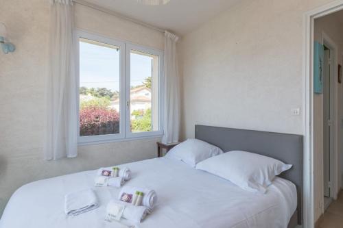a bedroom with a white bed with a window at L'Horizon - Vue mer - Parking - Jardin in Préfailles
