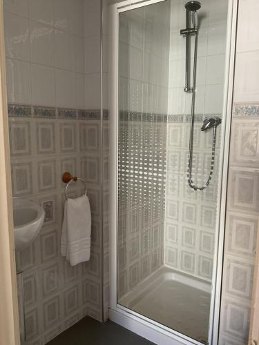 a shower with a glass door next to a sink at The Brentwood Hotel Porthcawl in Porthcawl