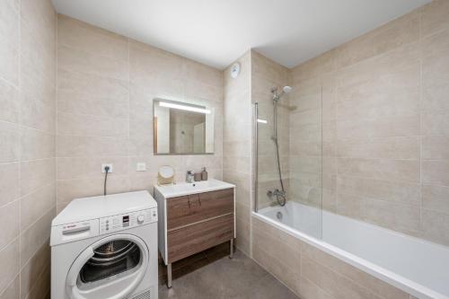 une salle de bain avec un lave-linge et une baignoire dans l'établissement Appartment hypercentre Evian, à Évian-les-Bains