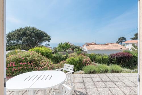 a white table and chairs on a patio with flowers at L'Horizon - Vue mer - Parking - Jardin in Préfailles