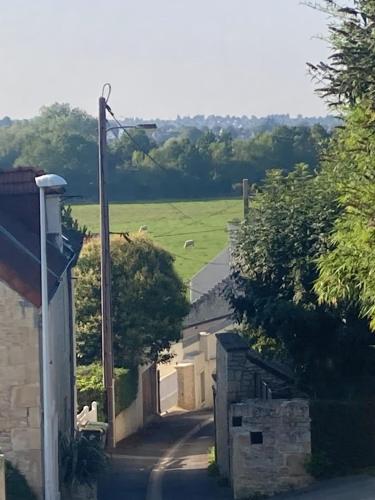 a view of a road and a field from a house at La cabane, Chambre indépendante dans jardin - Esprit cabane authentique et confortable - la campagne à 5 mn du centre de Caen in Fleury-sur-Orne