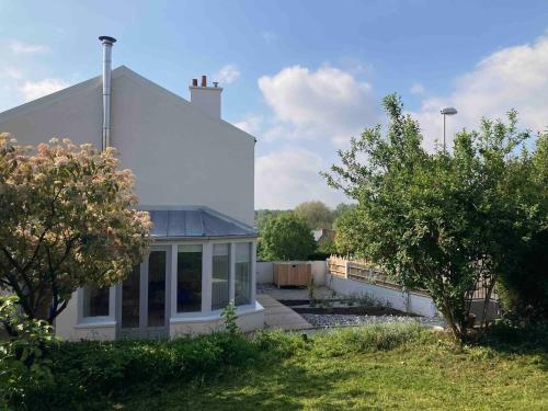 a white house with large windows on the side of it at La cabane, Chambre indépendante dans jardin - Esprit cabane authentique et confortable - la campagne à 5 mn du centre de Caen in Fleury-sur-Orne