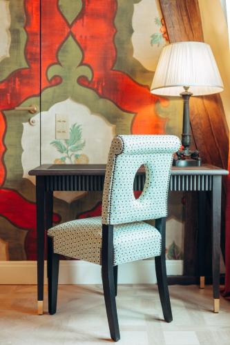 a chair sitting next to a desk with a lamp at Maison Barrière Vendôme in Paris