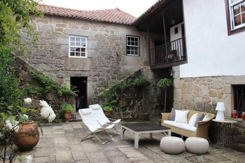 a patio with white chairs and a table and a building at CASA GRANDE DE JUNCAIS - SERRA DA ESTRELA in Fornos de Algodres
