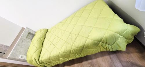 a bed with a yellow comforter on the floor at Vacansis Habitaciones y Alojamientos A Coruña in Visma