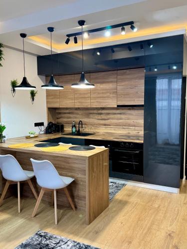 a kitchen with a wooden counter and white chairs at Cozy Flat in Baia Mare