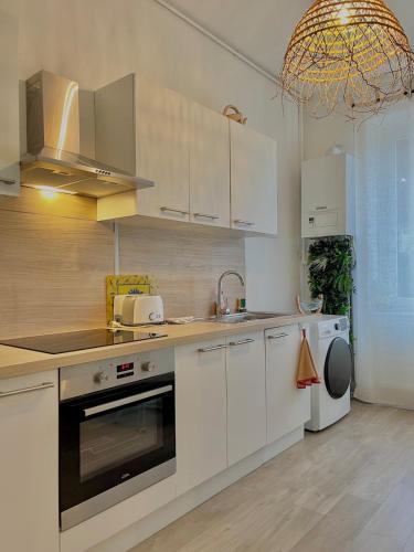 une cuisine avec des armoires blanches, un évier et un lave-vaisselle dans l'établissement L'universal Provençal au coeur de Mulhouse, à Mulhouse