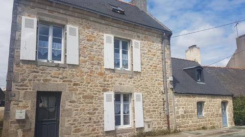 un ancien bâtiment en briques avec des fenêtres blanches et une porte dans l'établissement Maison historique - cour - centre-ville -plage 10 mn, à Pont-lʼAbbé