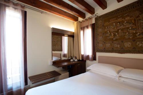 a bedroom with a white bed and a mirror at Ca' Dei Dogi in Venice