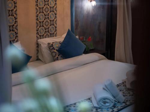 a bedroom with a white bed with blue pillows at Dar Ba Sidi & Spa in Chefchaouen