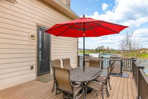 a table and chairs with a red umbrella on a deck at Lakefront Haven in Maynardville