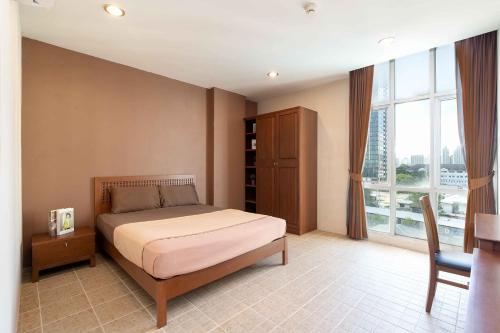 a bedroom with a bed and a desk and a window at 181 Ekkamai Apartment in Bangkok