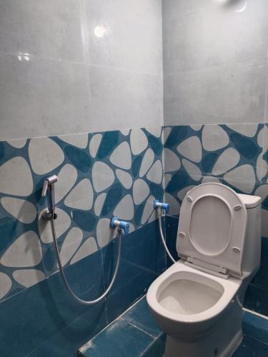 a bathroom with a toilet with a hose on the wall at Sithaphal tree villa in Hospet